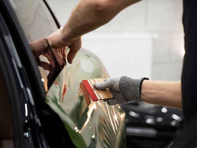 Cropped image of Hands of worker doing window tinting.